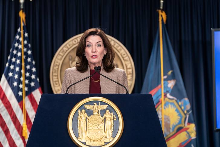 Gov. Kathy Hochul speaks from behind a podium emblazoned with a gold state seal